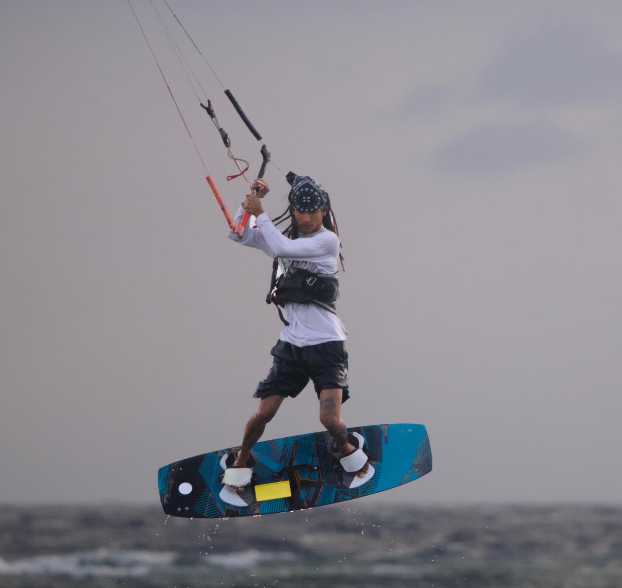 Local Siquijor kitesurf instructor boosting a jump on a blue kiteboard