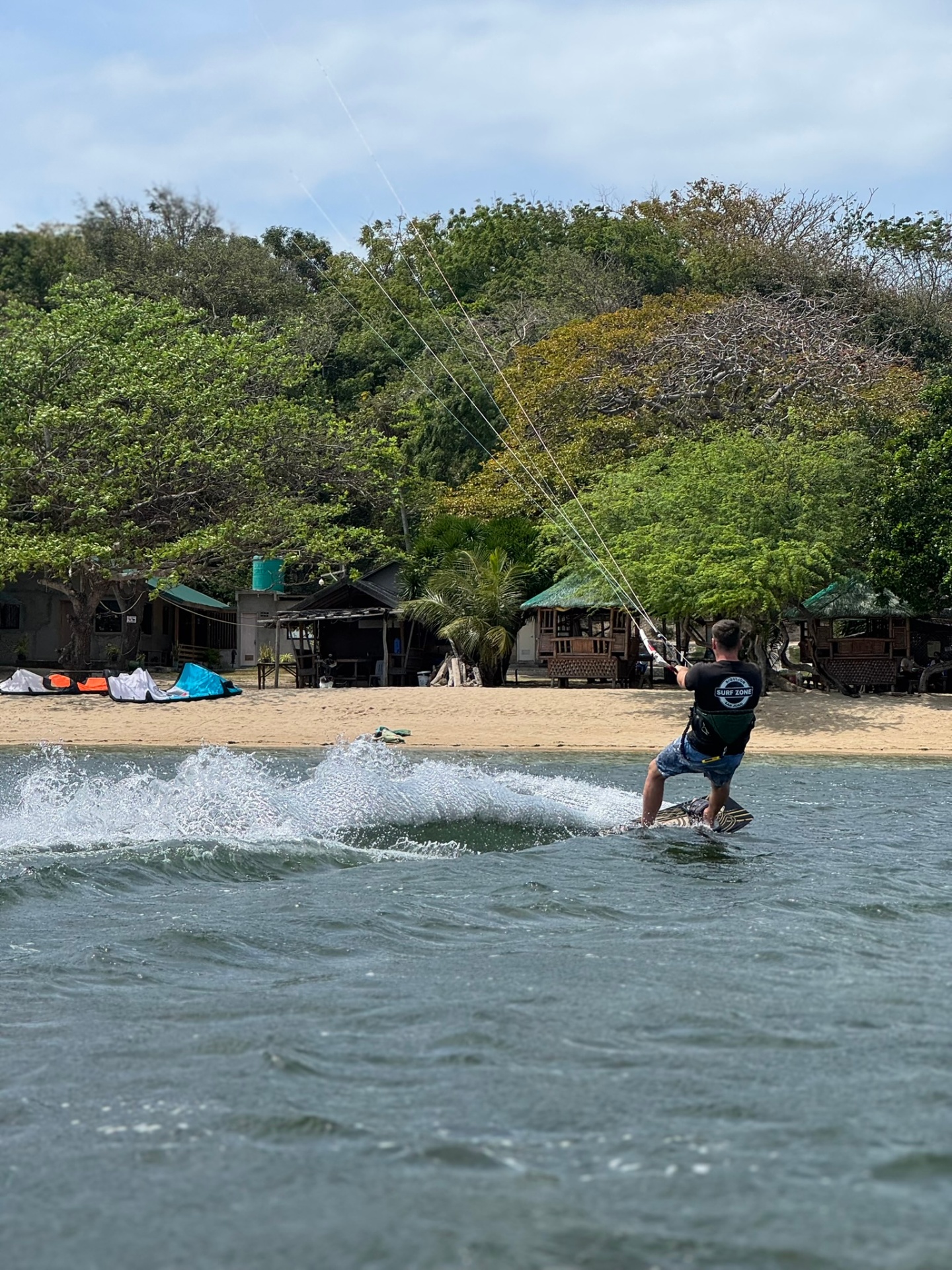 Kitesurfer riding back towards the beach with a spray of water
