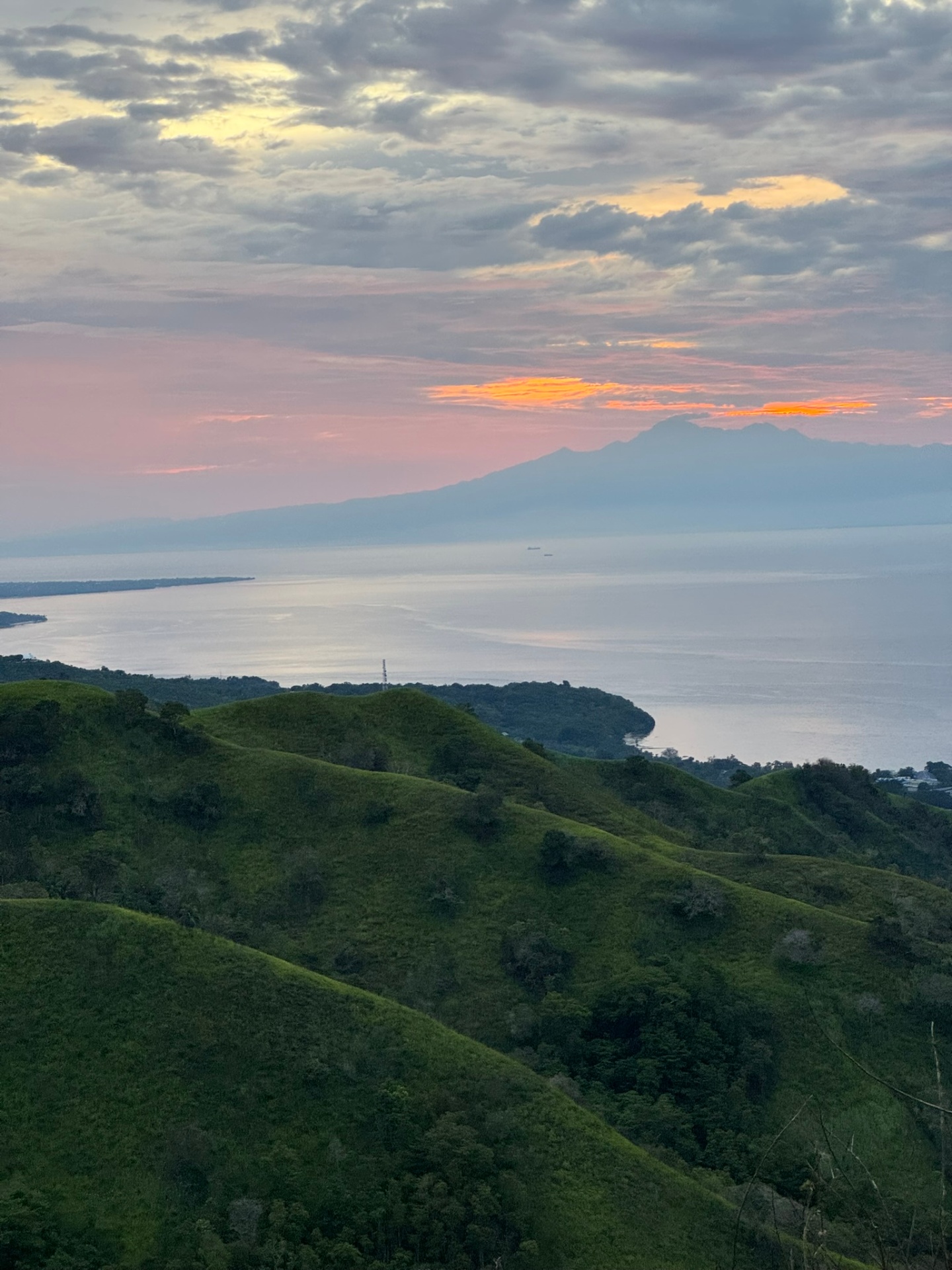 View of distant mountains across the sea at sunset