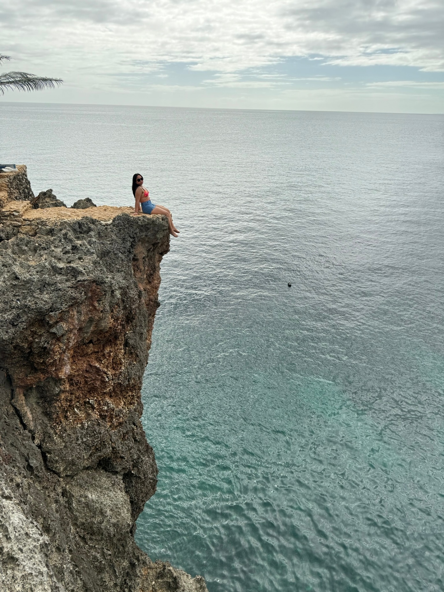 Sitting on a cliff edge above turquoise water