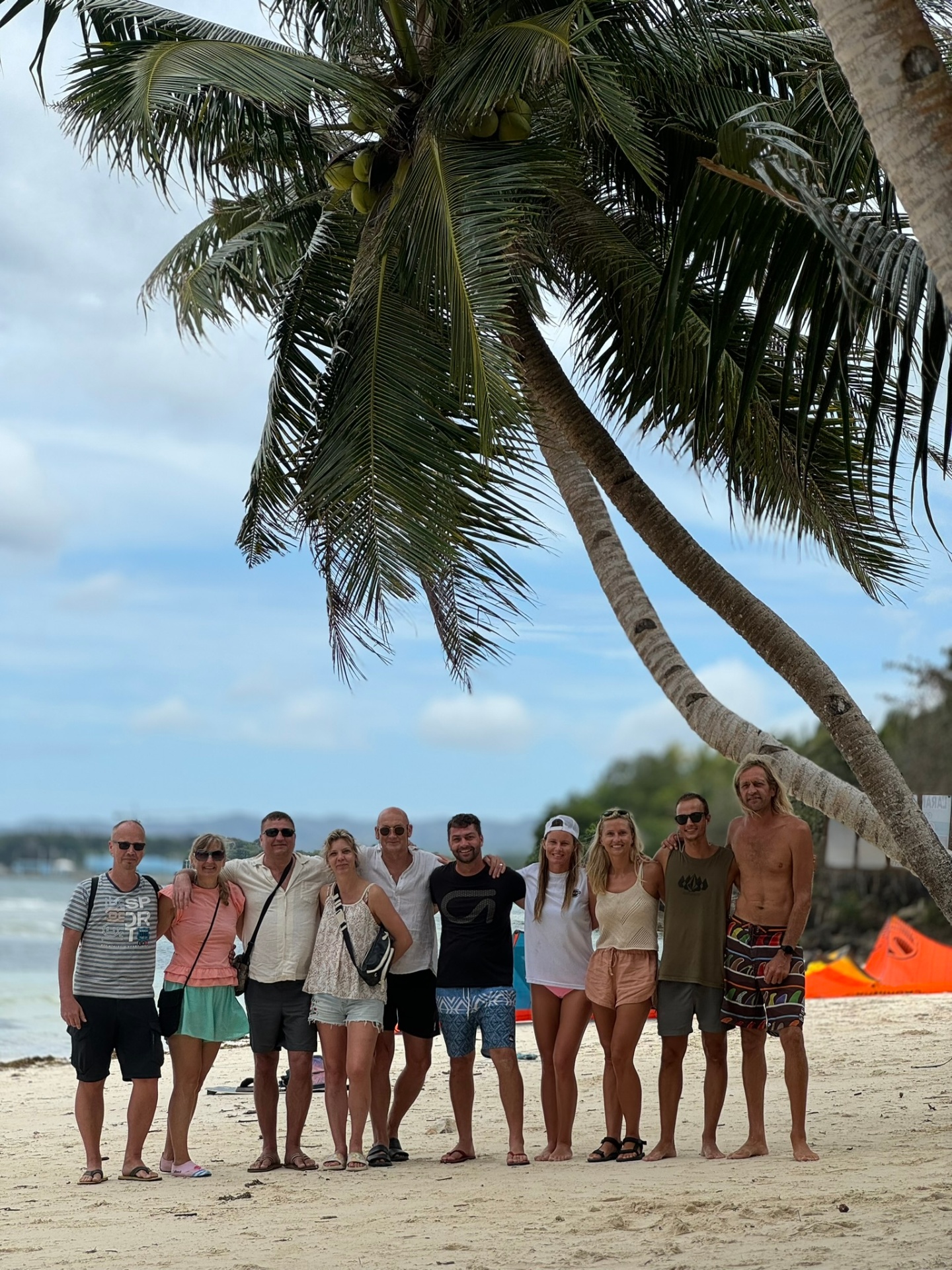 Group of travellers under a leaning palm on the beach