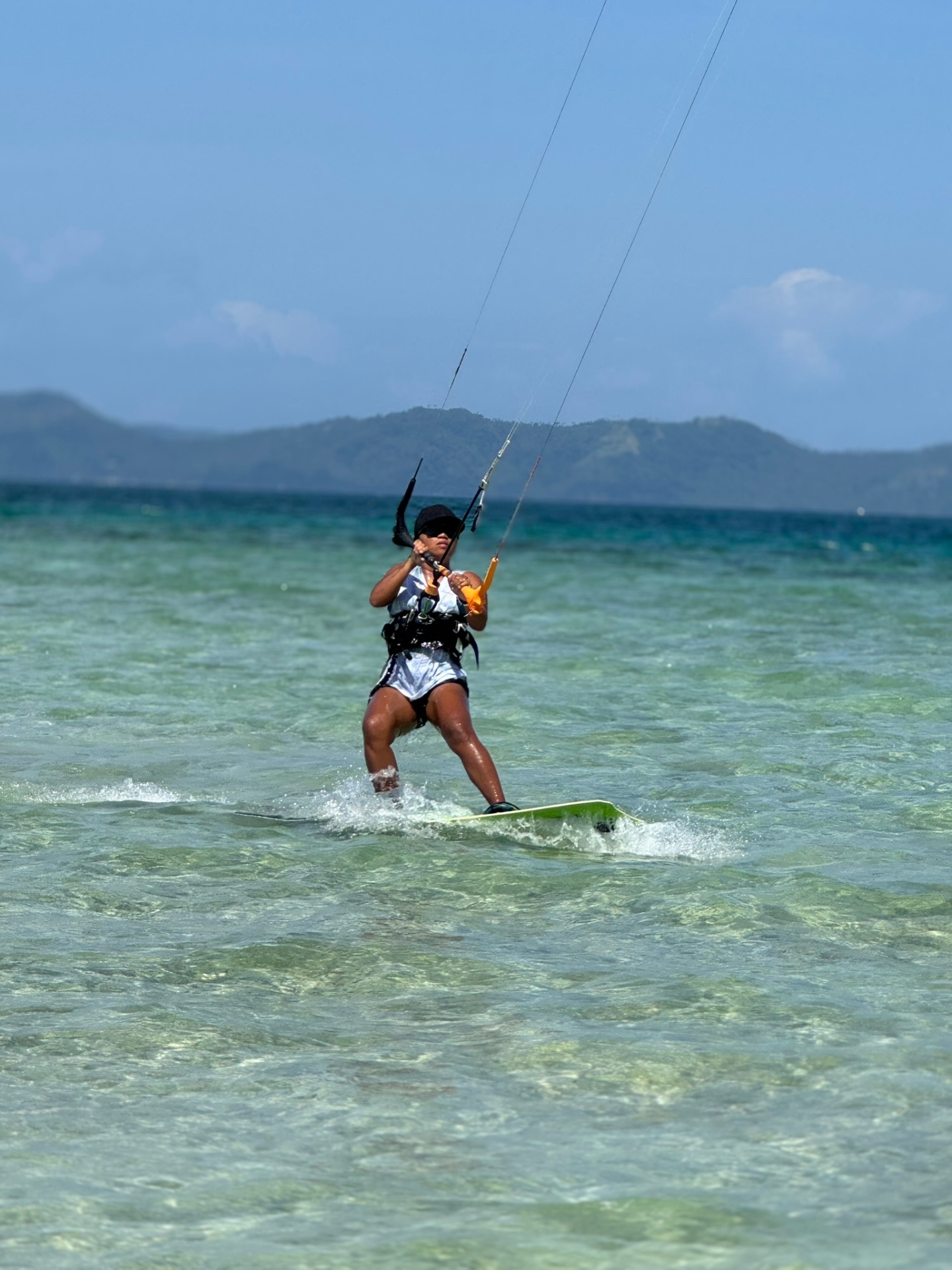 Local kitesurfer riding over turquoise water